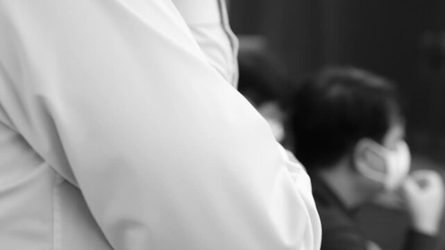 흑백 톤의 회의실에서 두 손을 맞잡고 긴장감을 풀거나 생각에 잠겨 있는 직장인의 모습