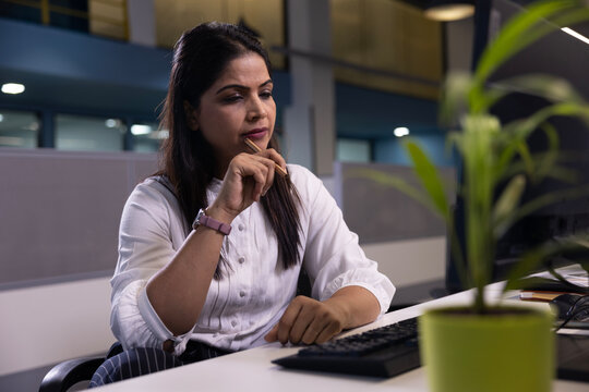 Indian thoughtful business woman thinking, worried serious about something while sitting front open portable laptop for client work. long hours of work concept