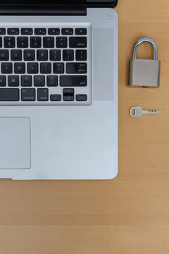 Vertical top view of laptop with padlock and key on wooden desk