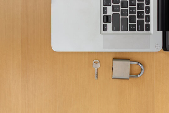 Top view of laptop with padlock and key on desk with copy space