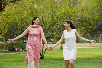 Obraz premium Young Indian girl spending quality time and fun with her mother in a beautiful green park, enjoying a happy family moment together outdoors.