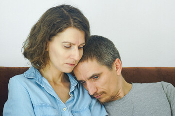 Obraz premium Tired man leaning head against woman's shoulder while seeking comfort during a difficult moment. Reflects emotional caregiving, male vulnerability, and psychological safety in intimate relationships.