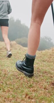 Person, legs or hiking with boots or walking stick on grass field for adventure, journey or trip. Active, closeup or hiker with shoes or aid for physical activity or trekking exercise in forest