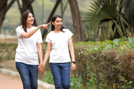 A elderly mother and an adult young daughter met on the track in park and embrace. Happy family, continuity of generations. Mothers Day. Indian happy mother and daughter spending time together at park