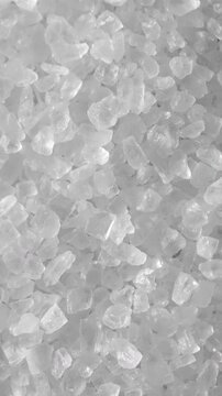 Salt Crystals Slowly Pouring in Macro. Extreme close-up of coarse salt crystals falling slowly and forming a granular cascade.	