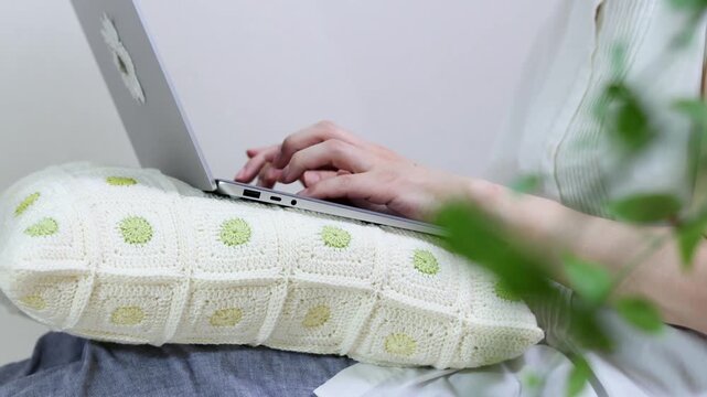 膝にノートパソコンを乗せて作業をする人