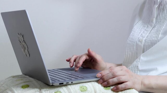 膝にノートパソコンを乗せて作業をする人