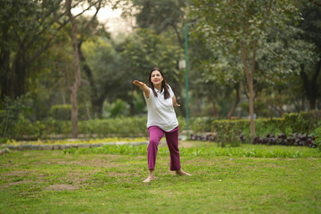 Fototapeta premium Indian active woman doing relaxes in yoga poses in green nature.