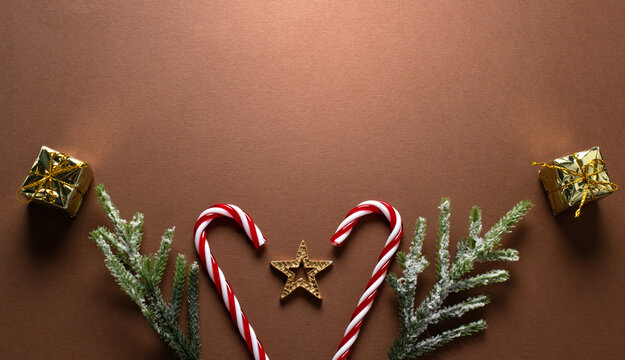 Christmas banner background with decorative candy canes, golden gift boxes, fir branch, star and cones for tree decoraton. New Year winter holiday composition with decor and space for text, top view.