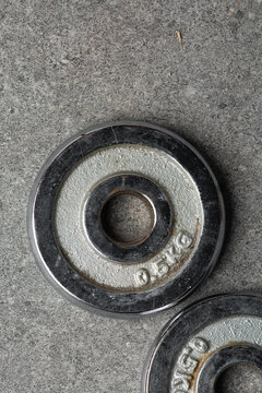 Overhead view of 2.5kg steel weights on a grey countertop, top view of small steel weights for weight and strength training on a grey countertop, concept photo for fitness and workouts