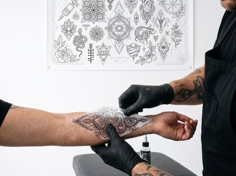 Tattoo Artist Applying Snake Design Stencil on Client's Forearm