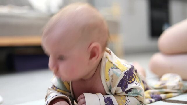 An irritable small child is trying to hold up their head while lying on their tummy.