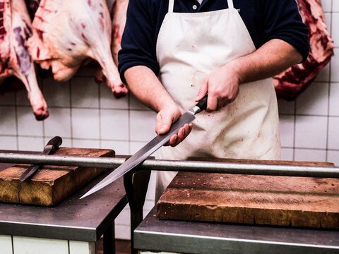 Butcher Sharpening Knife in Meat Shop