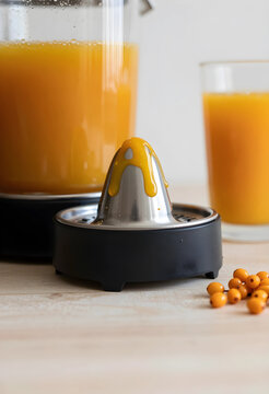 Sea buckthorn juice dripping from citrus juicer in kitchen