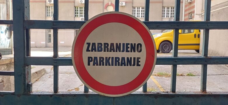 Rundes Parkverbotsschild &bdquo;Zabranjeno Parkiranje&ldquo; an einem eisernen Einfahrtstor