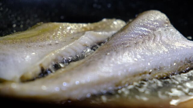 Cooking Indoors pan grilled seasoned Cod fillets on Stovetop, iron cast pan, close up boiled oil, deep fried.