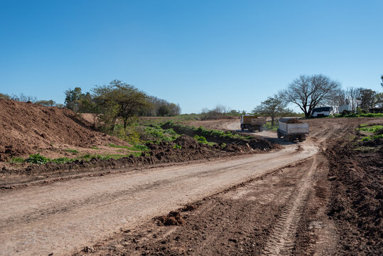 Construction trucks driving along dirt road during earthworks project