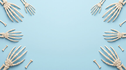 Fototapeta premium Multiple human skeleton hands arranged as a frame on a solid light blue background with copy space