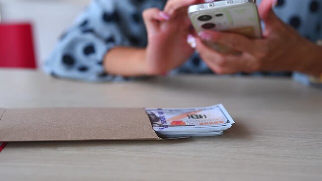 Woman handles bribery payment, negotiating bribery terms inside brown envelope after receiving digital payment under secret bribery deal.