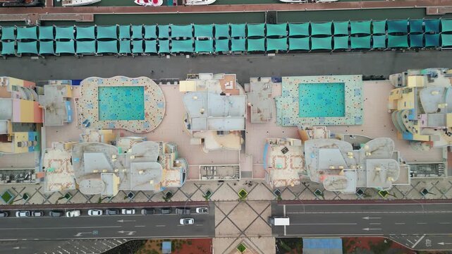 Aerial view of the Albufeira resort complex featuring turquoise swimming pools, modern rooftops, and adjacent coastal roads in Albufeira, Faro District, Portugal.