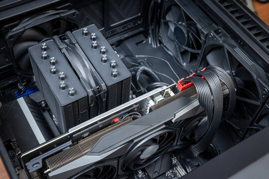 Internal components of an expensive gaming PC. A powerful gaming graphics card is installed on the motherboard in an open desktop computer case beside a dual-tower CPU cooler
