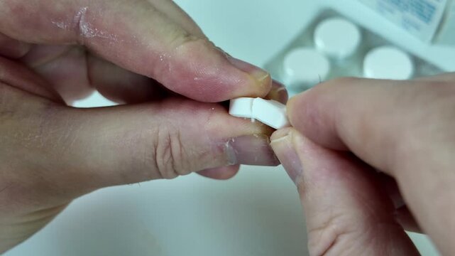 White Tablet Held Between Fingers in Close Up