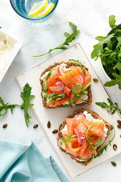 Salmon toast with cream cheese, red onion and arugula on whole grain bread, top view