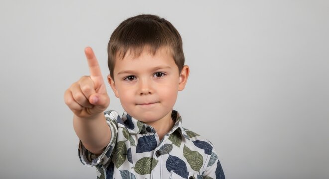Little boy pointing his finger forward looking at camera with a serious and focused expression in a studio portrait