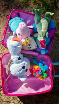Sosnovy Bor, Russia &mdash; August, 26, 2026: Soft toys packed in a pink suitcase on the ground, Olaf, Pepa the pig