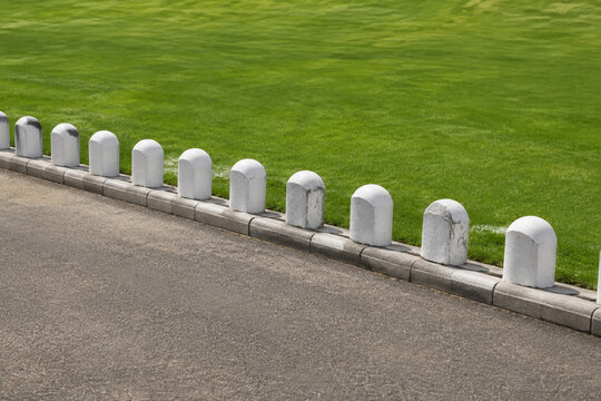 Row of white stone bollards and manicured lawn, boundary and landscaping concept