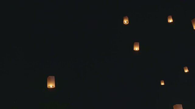 4K footage of many floating lanterns rising into the dark night sky. Yee Peng Festival celebration in Chiang Mai, Thailand. Traditional Thai Lanna culture and ceremony.