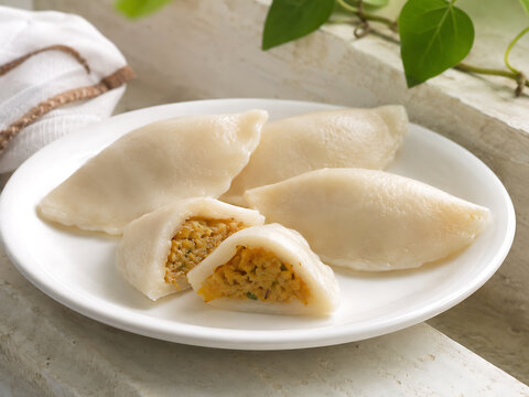 Traditional Bihari dal pitha, delicate rice-flour dumplings filled with seasoned lentils, one cut open for clear interior detail
