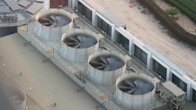 Large industrial cooling tower fans spin rapidly on the rooftop of a modern commercial building to provide air conditioning and ventilation