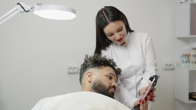 Trichologist showing hair follicles to male patient