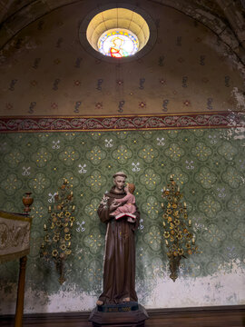 Statue of Saint Anthony of Padua holding the Christ child beneath a round stained-glass window, Gers, Sarrant, France