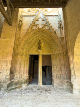 Gothic stone portal with carved tympanum and statue at the entrance of St. Peter collegiate church, Gers, La Romieu, France