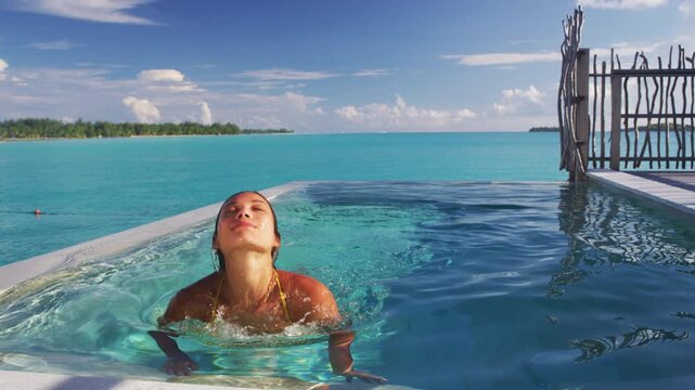 Sexy Asian bikini model woman coming out of water in infinity pool at luxury hotel resort in slow motion. Beautiful multiracial woman Raw unedited video of real woman model without makeup