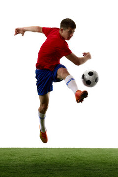 Leaping teen player striking football during aerial challenge. Concept of jumping ability, ball contact, competitive action and advanced football training.
