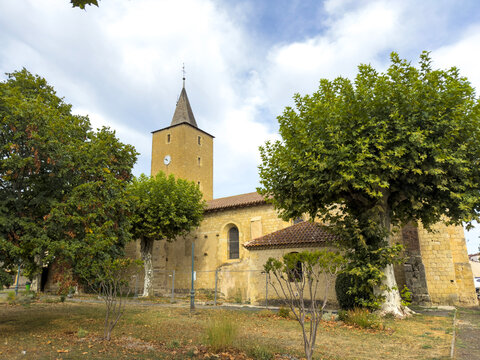 Stone bell tower of a Romanesque church rising above trees, Gers, Pavie, France