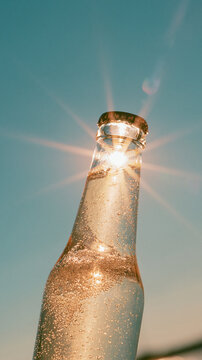 Sparkling beverage in glass bottle with bubbles and sunlight flare for summer refreshment advertising, drink promotion, beverage branding and commercial design
