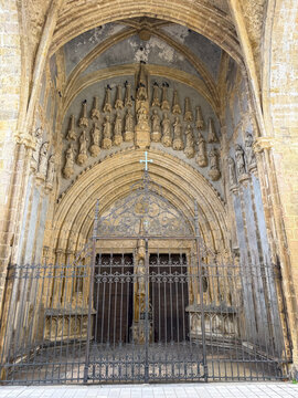 Gothic church portal decorated with carved saints and a wrought iron gate, Gers, Mirande, France