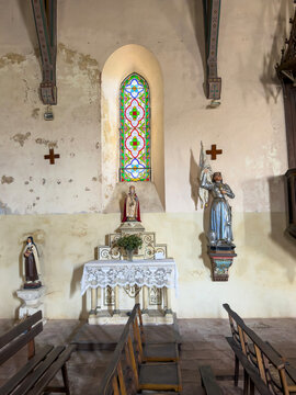Side chapel altar with statues of saints and colorful stained glass in the Church of Saint James the Greater, Gers, Tilliac, France