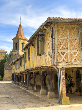 Village street lined with half-timbered houses leading to the church bell tower, Gers, Tilliac, France