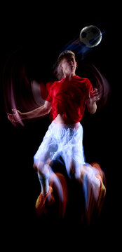 Motion trail follows jumping young footballer beneath airborne ball. Concept of vertical power, aerial timing, heading action and dramatic match promotion.