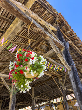 Hanging flower basket and bunting under the wooden roof of the covered market hall, Gers, Bassoues, France