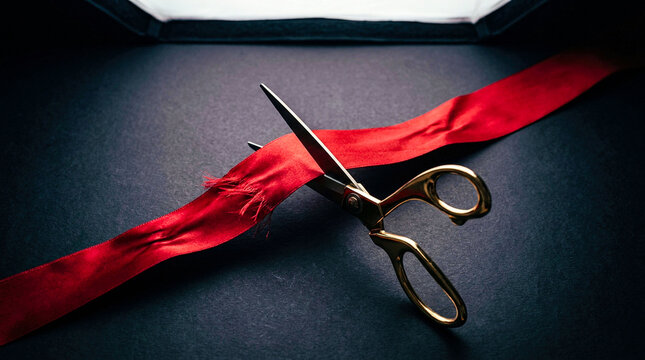 Golden ceremonial scissors cutting a red silk ribbon on a dark textured surface signifies grand opening events product launches and successful achievements.
