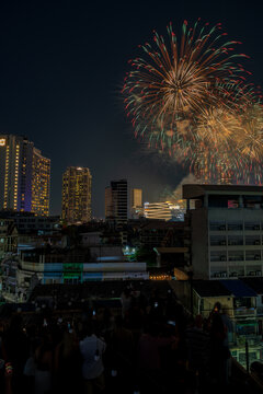 Bangkok, Thailand - 31 December 2025: View of New Year firework at Iconsiam illuminating the night sky above the city skyline with a crowd watching from a rooftop.