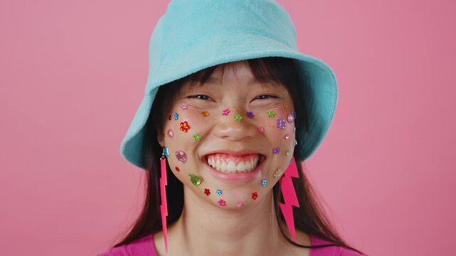 Beautiful asian woman portrait, young asian woman smiling with face stickers and pink background