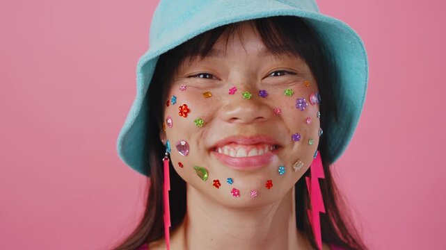 Beautiful asian woman portrait, young asian woman smiling with face stickers and pink background