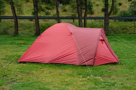 Bright red tent set up on lush green grass for a peaceful outdoor trip